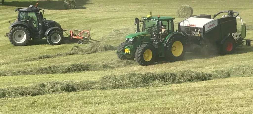 Traktor mit Ballenspresse am Feld - landwirtschaftliche Dienstleistung Traktor mit Ballenspresse am Feld - landwirtschaftliche Dienstleistung